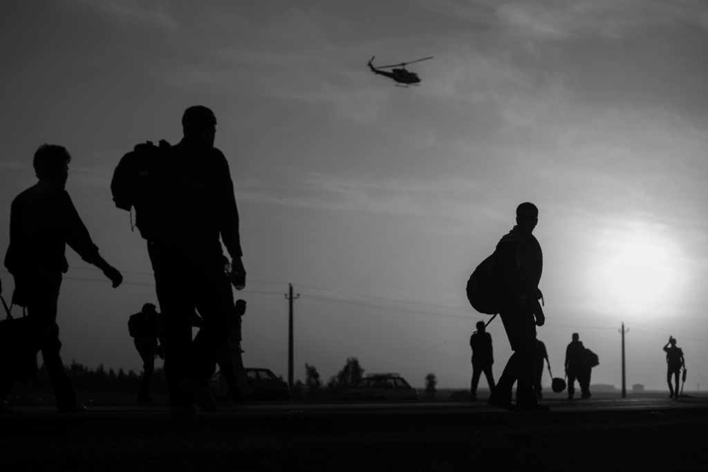 soldiers walking with helicopter overhead